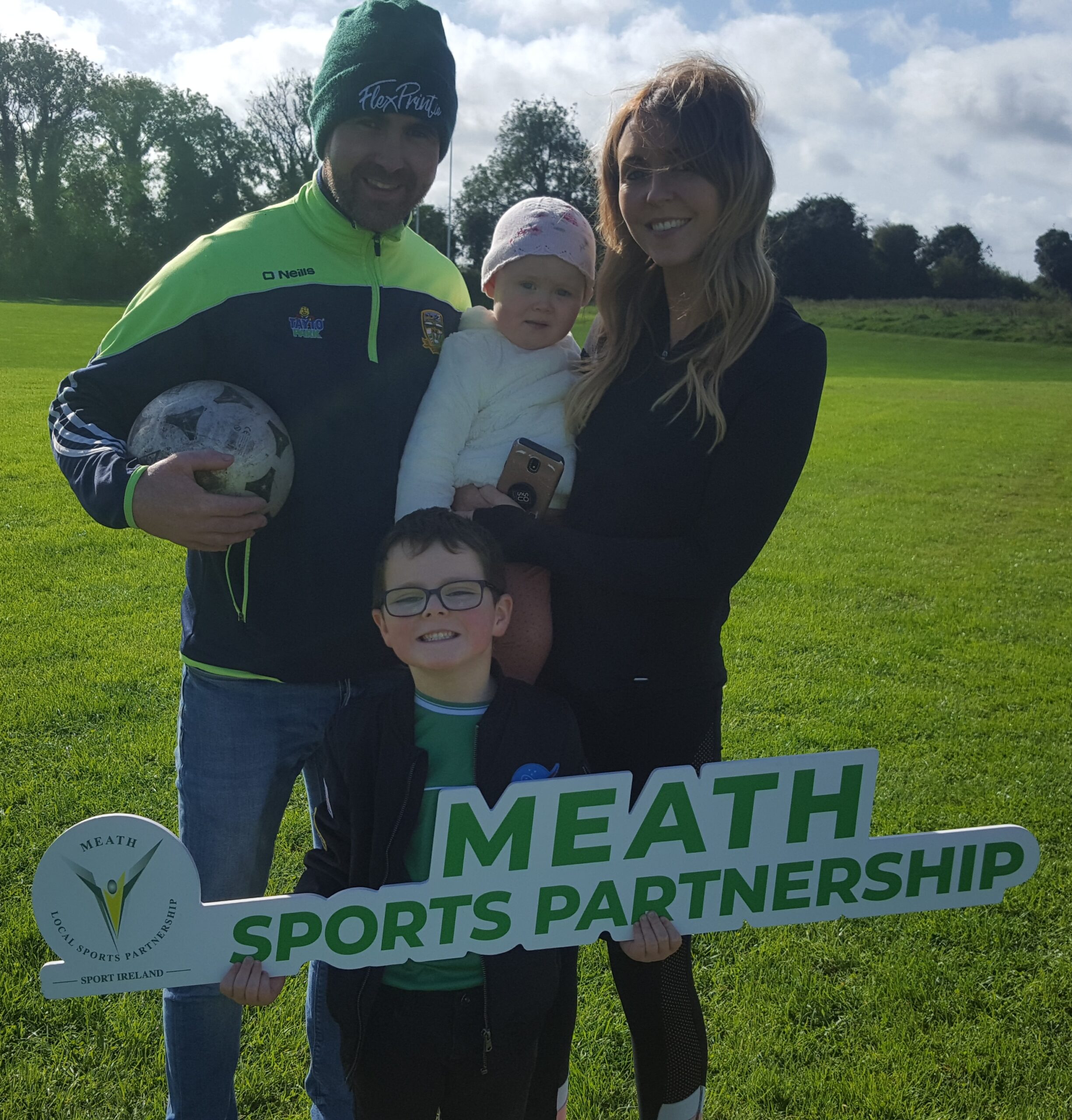 Family holding a ball in park