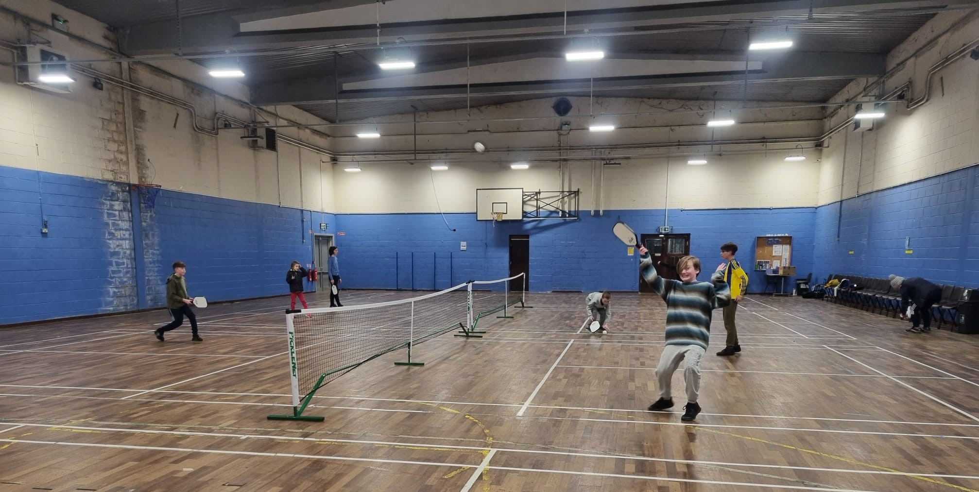 Kids playing pickleball in a hall