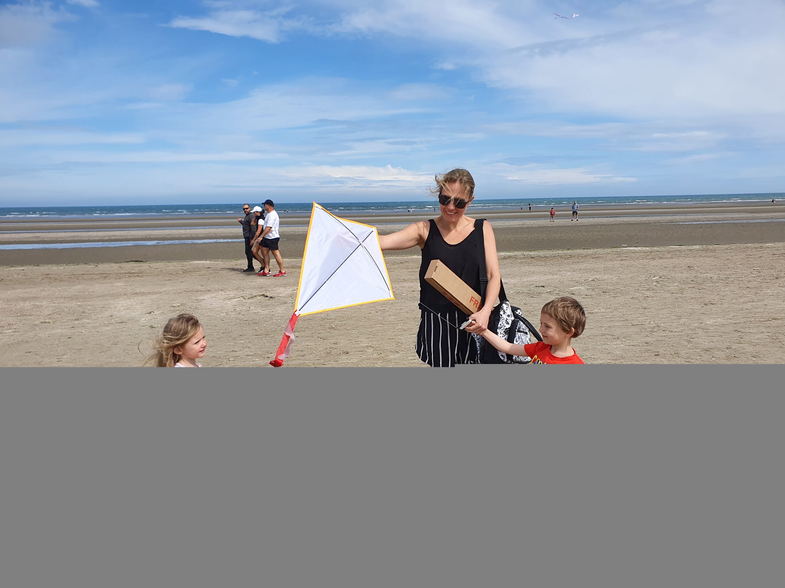 Mother and children holding kite on beach
