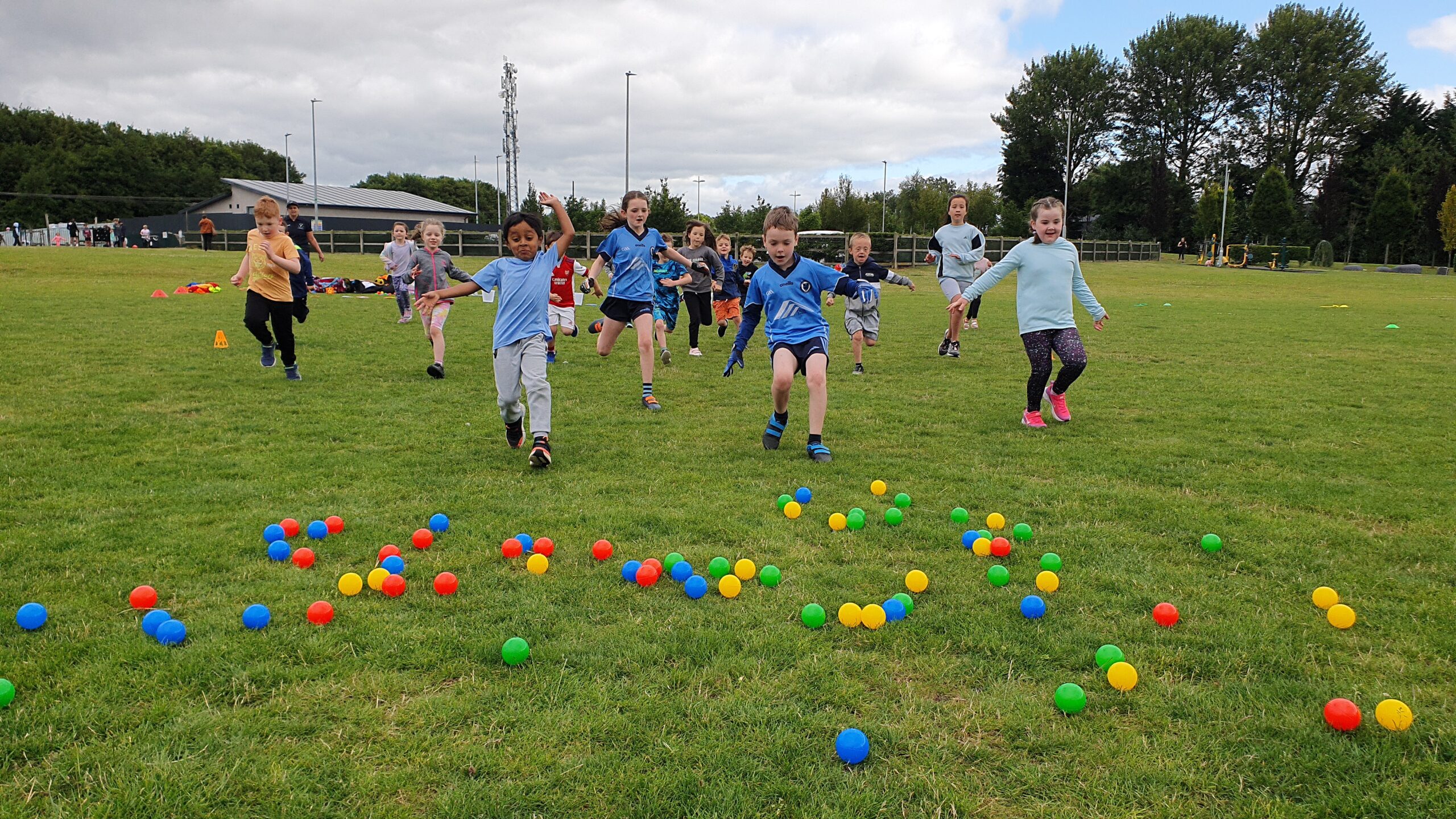 Children running towards balls on grass