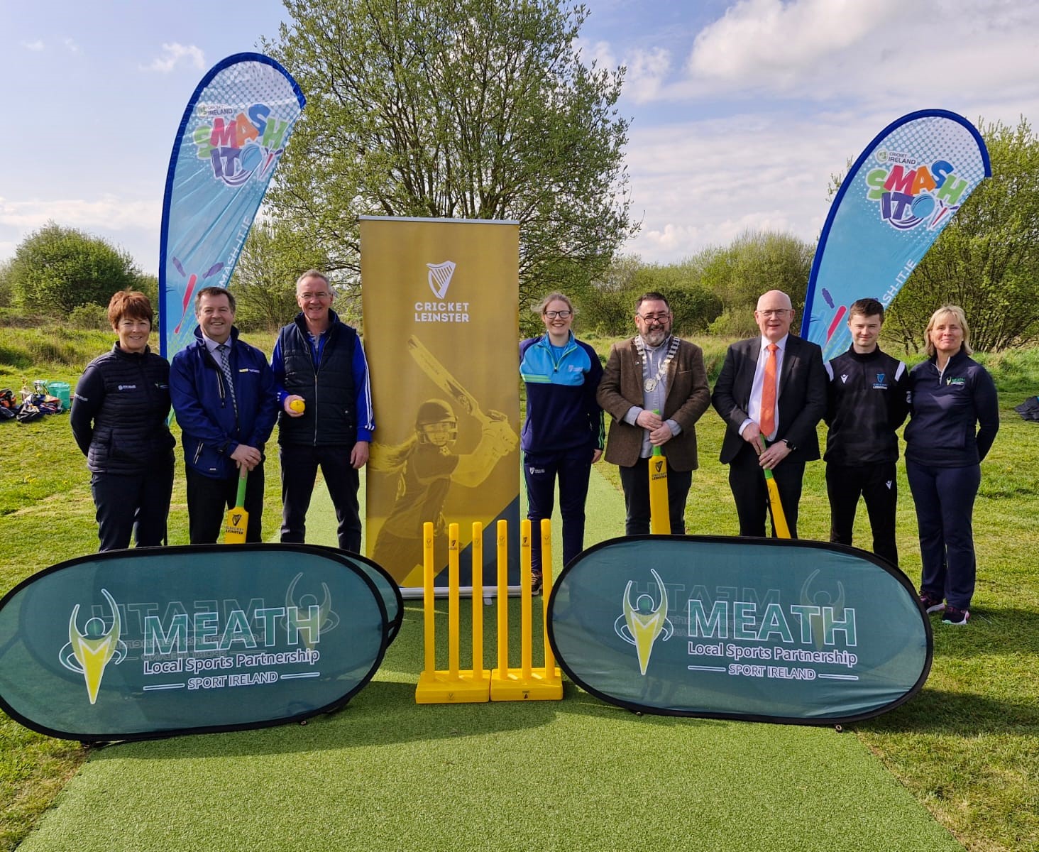 Group standing with cricket bats on a new wicket strip