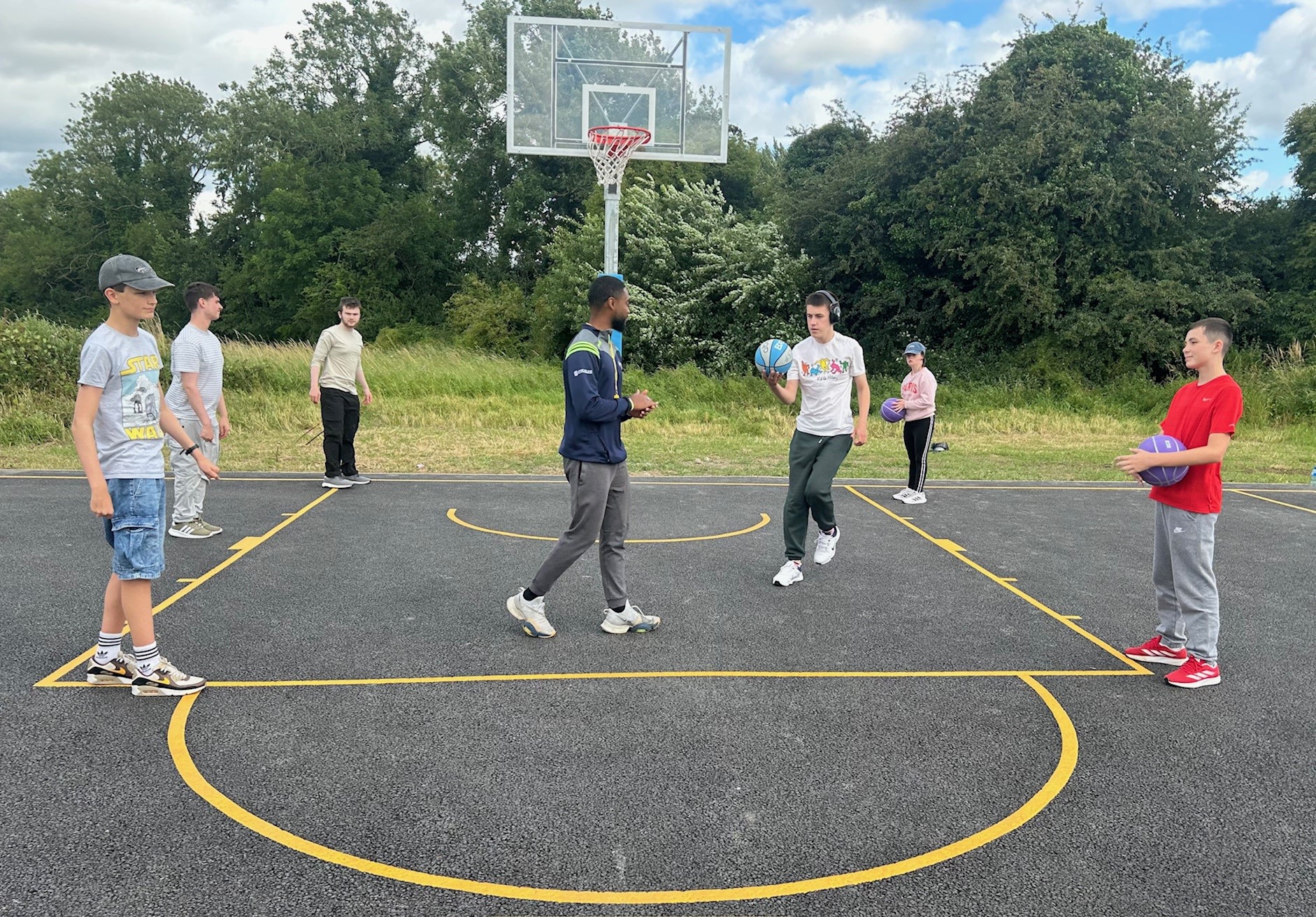 Young adults playing 3x3 basketball with a coach