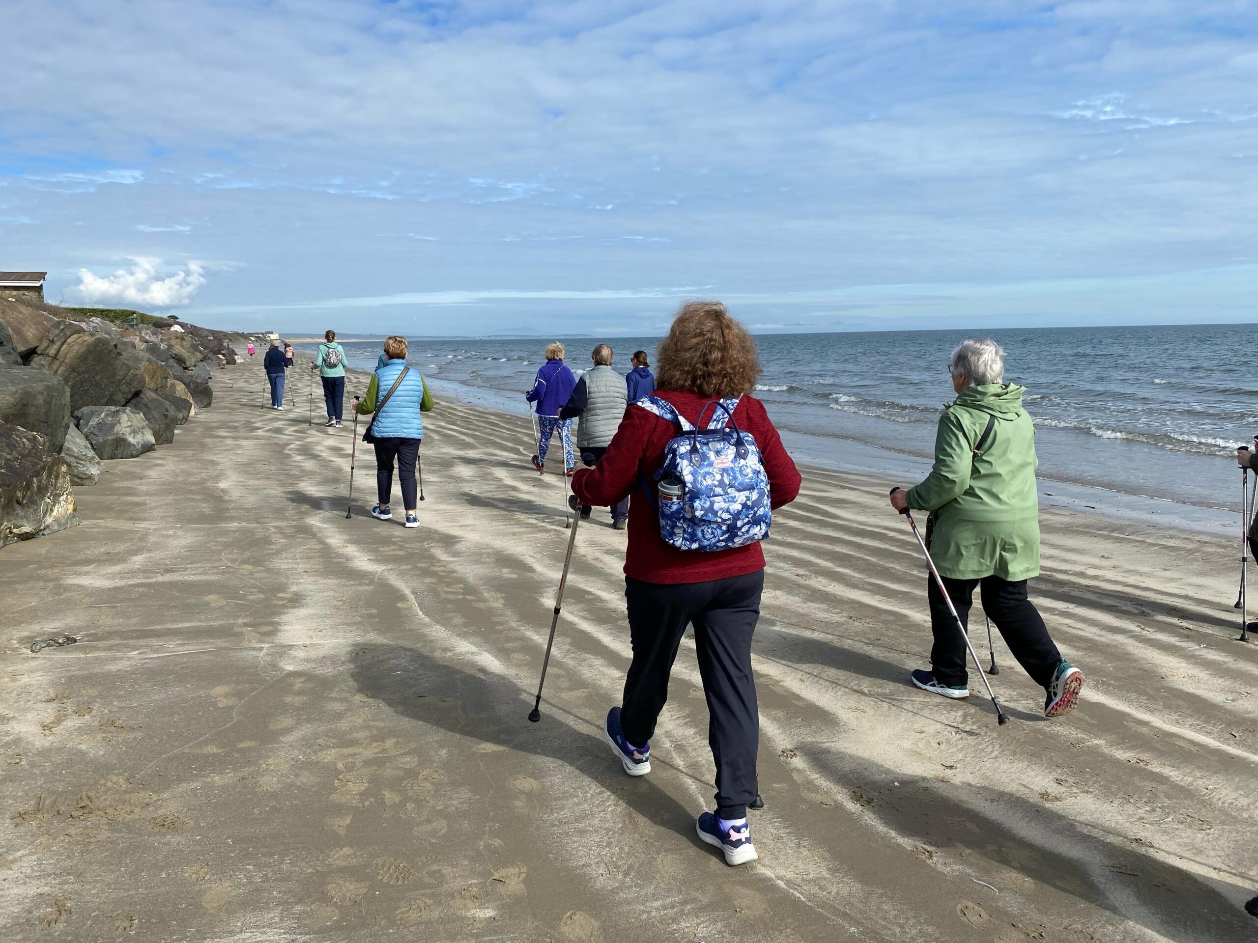 A group of people walking on beach with activator poles
